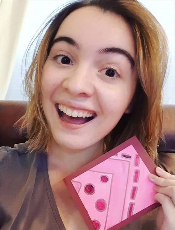 A woman holding a notecard and smiling